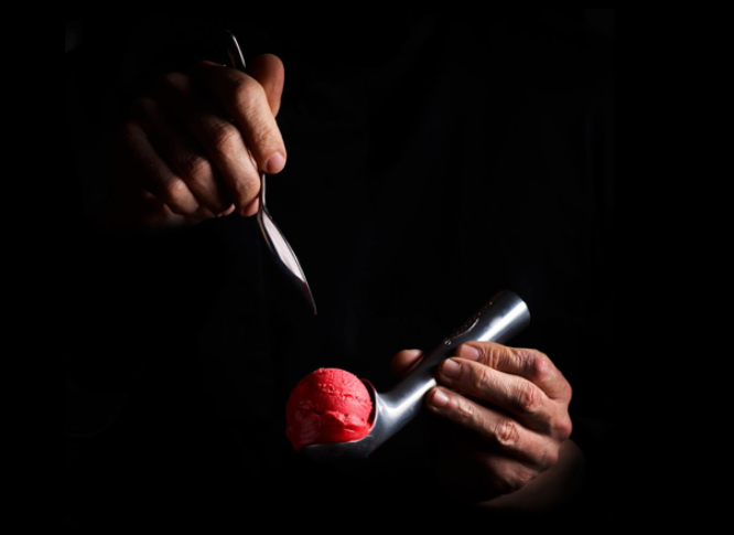 2 mains tenant une boule de glaces dans un fond noir avec la boule de glaces en rose 